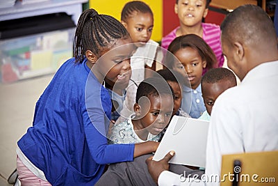 Teacher showing kids a book during elementary school lesson Stock Photo