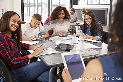 Teacher sitting with high school students using tablets Stock Photo