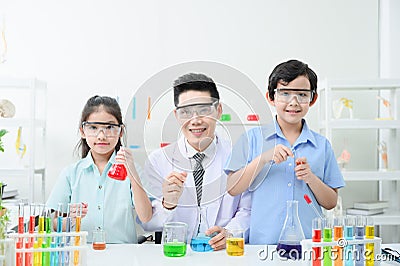 Teacher and students are looking at the camera while doing science experiments Stock Photo