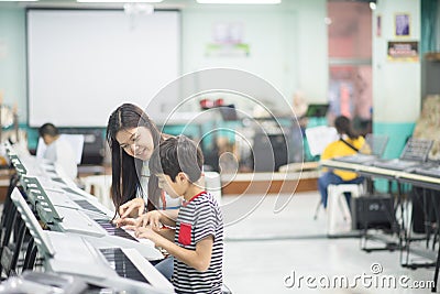 Teacher teach keyboard electone instument to a boy in the class room Stock Photo