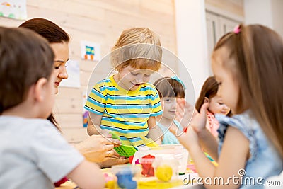 Teacher teaches kids modeling clay in playroom at kindergarten Stock Photo