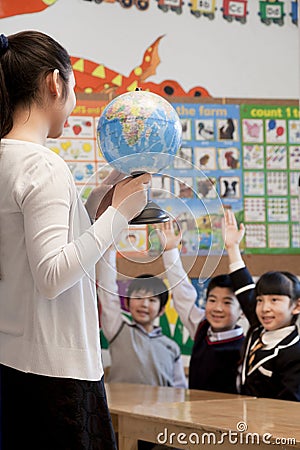 Teacher teaching geography to schoolchildren with a globe Stock Photo