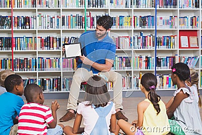 Teacher teaching kids on digital tablet in library Stock Photo