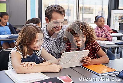 Teacher using tablet with two pupils in school class Stock Photo