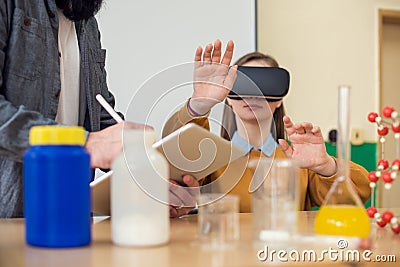 Teacher using Virtual Reality Glasses and 3D presentation to teach students in chemistry class. VR, Tutoring, New Technologies. Stock Photo