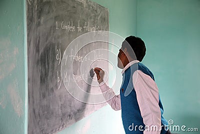 Teacher writes on blackboard Editorial Stock Photo