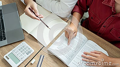 Teaching helping technology concept. Woman young teacher or tutor with adult students in classroom at desk with papers, laptop Stock Photo