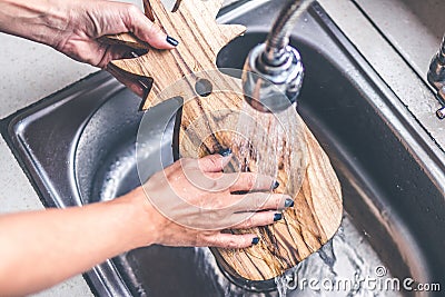 Teak wooden cutting board washing. Woman hands washing teak cutting board. Stock Photo