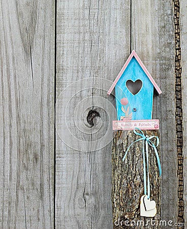 Teal blue birdhouse perched on top of post with wooden hearts Stock Photo