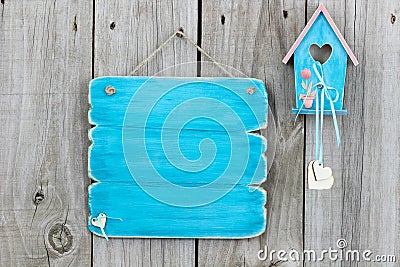 Teal blue blank sign next to blue and pink birdhouse hanging on fence Stock Photo