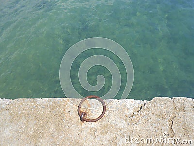 Teal waters and an iron ring in a dock Stock Photo