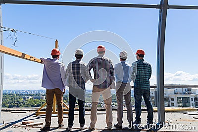 Team Of Builders On Costruction Site Back Rear View, Foreman Group In Hardhat Outdoors Partnership And Teamwork Concept Stock Photo