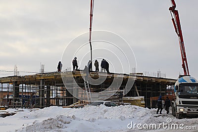 The team of builders working on the construction of the building in Novosibirsk, in the winter of poured concrete using a special Editorial Stock Photo