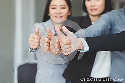 Team of business join forces working and showing thumbs up as si Stock Photo