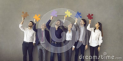 Team of business professionals standing together and holding colorful pieces of jigsaw puzzle Stock Photo