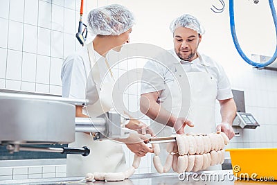 Team of butchers filling sausage in meat industry Stock Photo