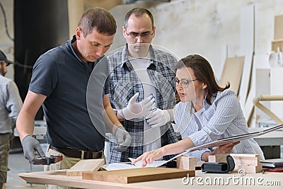 Team of carpenters workshop workers discussing a furniture project with client, designer, engineer Stock Photo