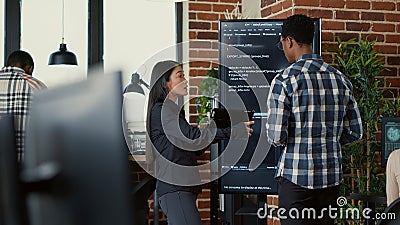 Team of coders analyzing code on wall screen tv comparing errors using digital tablet Stock Photo