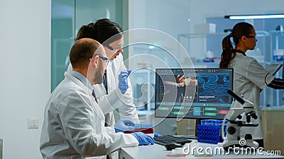 Team medical scientist conducting DNA experiments looking in computer Stock Photo