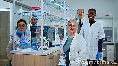Team of multiethnic scientists sitting in laboratory looking at camera Stock Photo