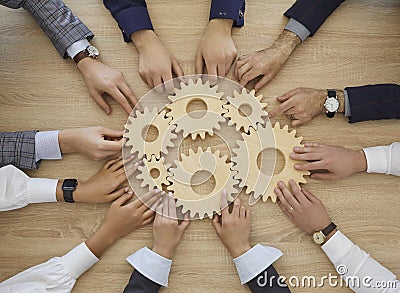Team of people join cogwheels as metaphor for teamwork and effective business system Stock Photo