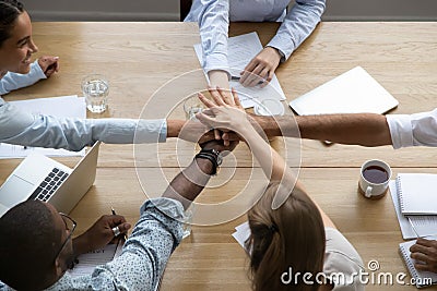 Team people stacking hands together over table engaged in teambuilding Stock Photo