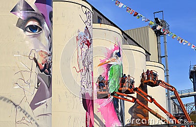 Team of artists painting murals on silos in idustrial zone Editorial Stock Photo