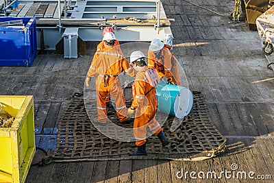 A team of riggers or roughnecks handling oil drum Stock Photo