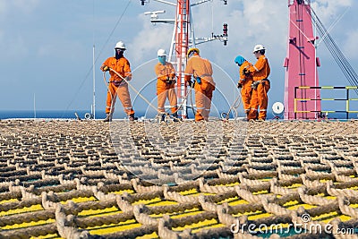 A team of riggers or roughnecks installing landing net on a helipad of a construction work barge Editorial Stock Photo