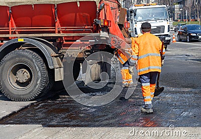 A team of road workers with a hot asphalt truck repairing a section of the road Editorial Stock Photo