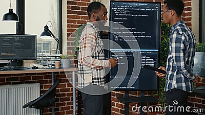 Team of software engineers leaving after analyzing source code on wall screen tv comparing errors Stock Photo