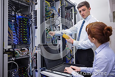 Team of technicians using digital cable analyser on servers Stock Photo