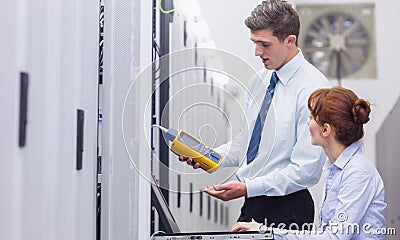 Team of technicians using digital cable analyser on servers Stock Photo