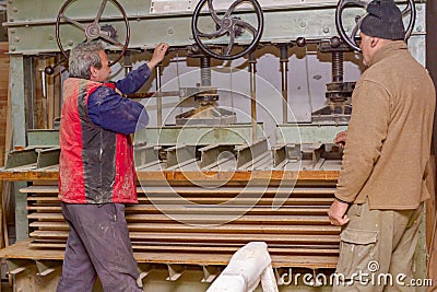 Carpenters tighten the press machine, squeeze wooden profiles smeared with glue, drying process Stock Photo