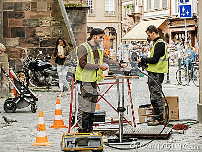 Team working near open manhole installing fiber optic Editorial Stock Photo