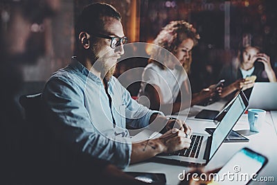 Team of young coworkers work together at night office.Young people using electronic gadgets at the table.Horizontal Stock Photo