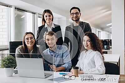 Teamwork concept.Young creative coworkers working with new startup project in modern office and looking at camera Stock Photo