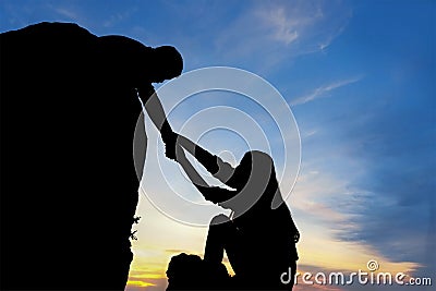 Teamwork couple helping hand trust assistance silhouette in mountains, sunset. Stock Photo