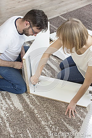 Teamwork. Husband and wife are turning furniture together in the living room. Stock Photo