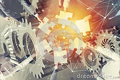 Teamwork of partners. Concept of integration and startup with puzzle pieces and gear overlay. double exposure with Stock Photo