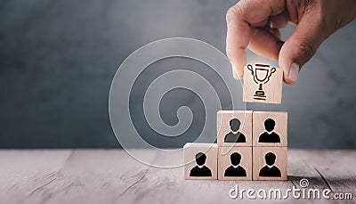 Teamwork and Success concept. Hand holding wood block with icon Trophy cup Stock Photo
