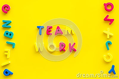 Teamwork training concept. Text teamwork lined with colored letters near toy letters on yellow background top view copy Stock Photo