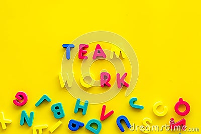 Teamwork training concept. Text teamwork lined with colored letters near toy letters on yellow background top view copy Stock Photo