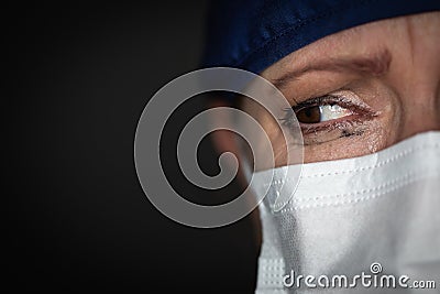 Tearful Stressed Female Doctor or Nurse Crying Wearing Medical Face Mask on Dark Background Stock Photo