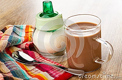 Spoon on napkin, sugar bowl, cocoa with milk in cup on wooden table Stock Photo