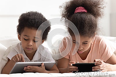 Tech addicted children using smartphone and tablet. Stock Photo