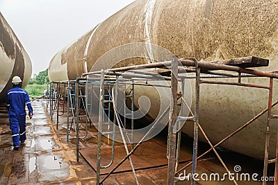 Technical engineer in mechanic jumpsuit with safety helmet on duty on deck with wind turbine tower and scaffolding Stock Photo