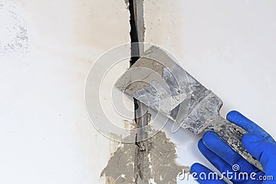 . technical hole in it is an electrical wire. the wall is white. Master with a spatula and mortar covers the cable Stock Photo