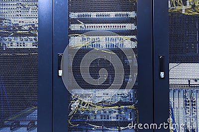 Technical wall of cellular data terminal in modern communication center. Close up backhaul network equipment under closed meshed Stock Photo