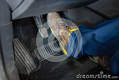 Technician with boots testing the brake pedal of a car during a vehicle inspection Stock Photo